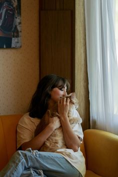 a woman sitting on a couch holding a cat