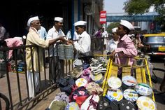 men in white hats are standing near a cart full of shoes and other items on the street