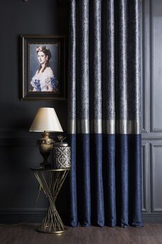 a room with a lamp and pictures on the wall, along with a blue curtain