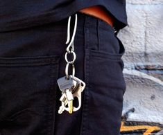 a person wearing black pants and holding a pair of keys in their pocket with both hands