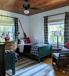 a bed room with a neatly made bed next to two chairs and a ceiling fan