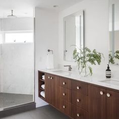 a bathroom with two sinks, mirrors and a shower stall in the middle of it