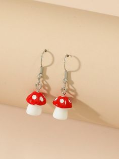 the red and white mushroom earrings are hanging from silver earwires on a woman's arm