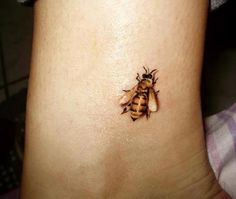 a small bee tattoo on the side of a woman's stomach, with an insect crawling on it