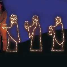 three lighted nativity figures standing in front of a blue background with lights on them