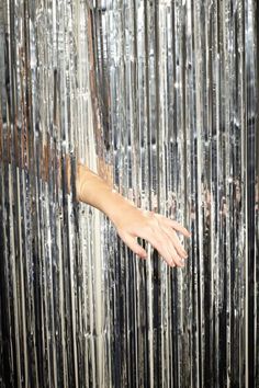 a person's hand reaching up against a metal curtain