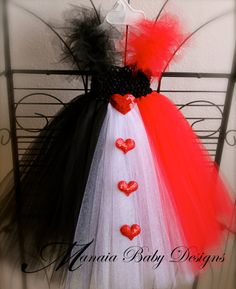 a red, white and black tulle dress with hearts on the bottom is hanging from a metal rack