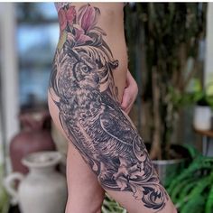 a woman's leg with an owl and flowers tattoo on the side of her body