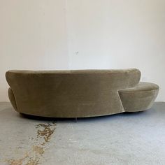 a large couch sitting on top of a cement floor next to a white wall in a room