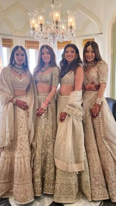 three women in matching outfits posing for the camera with chandelier and chandelier