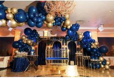 blue and gold balloons are hanging from the ceiling in front of a chandelier