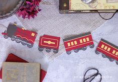 red and gray train decorations sitting on top of a table next to a pair of scissors