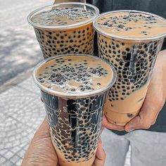 three people are holding two cups with liquid in them, one is filled with coffee and the other has leopard print