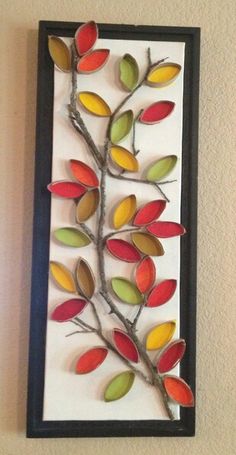 a decorative wall hanging made out of paper and metal branches with colorful leaves on it