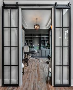 an open glass door leading to a kitchen and dining room with wood floors, white walls and black doors