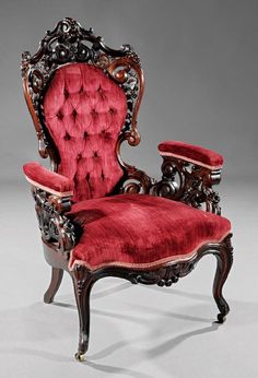 an ornately carved chair with red velvet upholstered seat