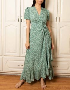 a woman standing in front of white closets wearing a green dress with floral print