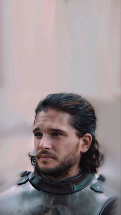 a man with long hair and beard wearing a suit of armor looking at the camera