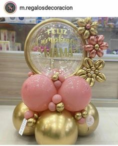 a pink and gold balloon clock on top of two balls in front of a store display