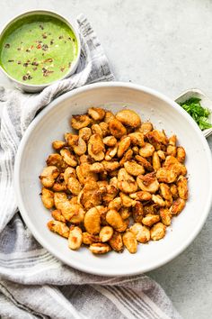 a white bowl filled with fried food next to a green sauce