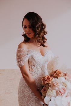 a woman in a wedding dress holding a bouquet and looking down at the camera with her hand on her hip