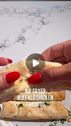 a person holding a piece of food in their hand with the caption air fryer buffalo chicken taquitos