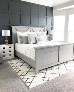 a bedroom with gray walls, white bedding and grey carpeted area rugs