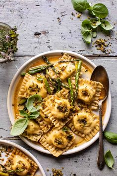 two plates filled with ravioli and asparagus on top of a wooden table