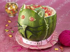 a watermelon shaped like a cat sitting on top of a plate with candy