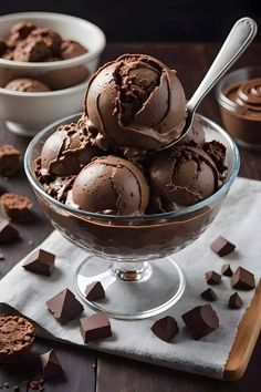 chocolate ice cream in a glass bowl with spoons on the side and pieces of chocolate next to it