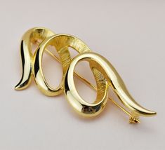 "Elevate your style with our stunning Huge Abstract Brooch in gold - the ultimate statement piece for fashion-forward women. This very large, quirky lapel pin is a vintage-inspired accent that adds a touch of retro charm to any jacket or outfit. Crafted for those who dare to be bold, its super chunky design guarantees that all eyes will be on you. Whether it's a special occasion or a unique everyday accessory, this brooch is the perfect choice. Give the gift of quirky elegance to someone special or treat yourself to this extraordinary piece of jewelry today! ❗️ Details: Vintage from the 1960s  Length: 3 Inches;  Width: 1.2 Inches  Materials: gold tone metal Style: Mid-century   36BJ 🎁 And if you happen to be a gentleman shopping for a gift for your lady, here's a couple of tips: 1) There' Cremation Jewelry Necklaces, Lapel Brooch, Big Necklace, Urn Necklaces, Chunky Jewelry, A Gentleman, Super Chunky, Everyday Accessories, Quirky Gifts