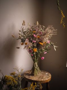 a bunch of flowers sitting on top of a wooden table in front of a wall