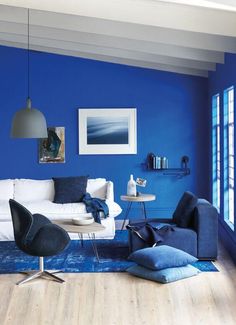 a living room with blue walls and white furniture in the center, along with a rug on the floor