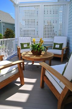 a wooden table sitting on top of a patio next to two chairs and a potted plant