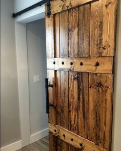 an open wooden door in a room with white walls and wood flooring on the side