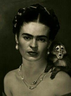 an old photo of a woman holding a monkey on her shoulder and looking at the camera