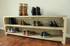 several pairs of shoes are lined up on a wooden shelf in front of a white wall