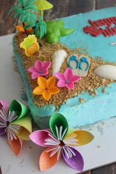 there is a cake decorated with flowers and sand on the table next to some scissors