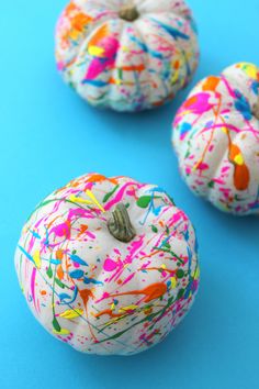 three painted pumpkins sitting on top of a blue surface