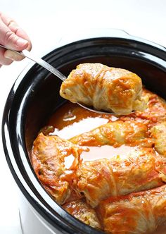 someone is spooning some food out of the slow cooker to make it look like they are eating