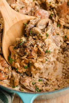 chicken and rice in a blue pot with a wooden spoon