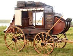 an old fashioned horse drawn carriage on the grass