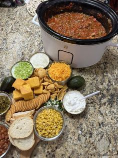 a crock pot filled with beans, cheese and crackers next to other foods