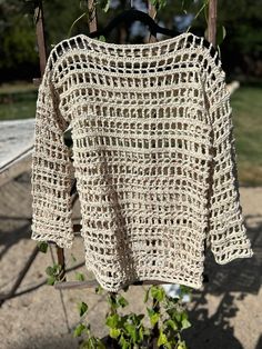 a crocheted sweater hanging on a clothes line in front of a tree branch