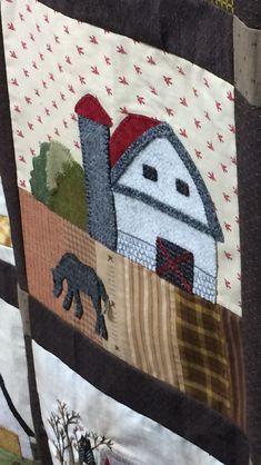 a quilted wall hanging with farm animals and barn in the background, along with trees