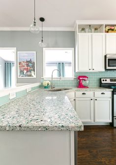 a kitchen with white cabinets and marble counter tops