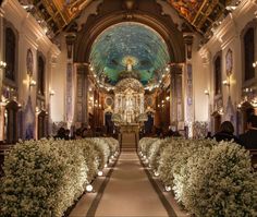 the inside of a church with many plants and flowers on either side of the aisle