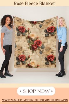 two women holding up a rose fleece blanket in front of a white background with roses on it