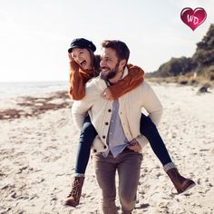 a man carrying a woman on his back at the beach