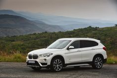 a white bmw suv parked on the side of a road in front of some mountains